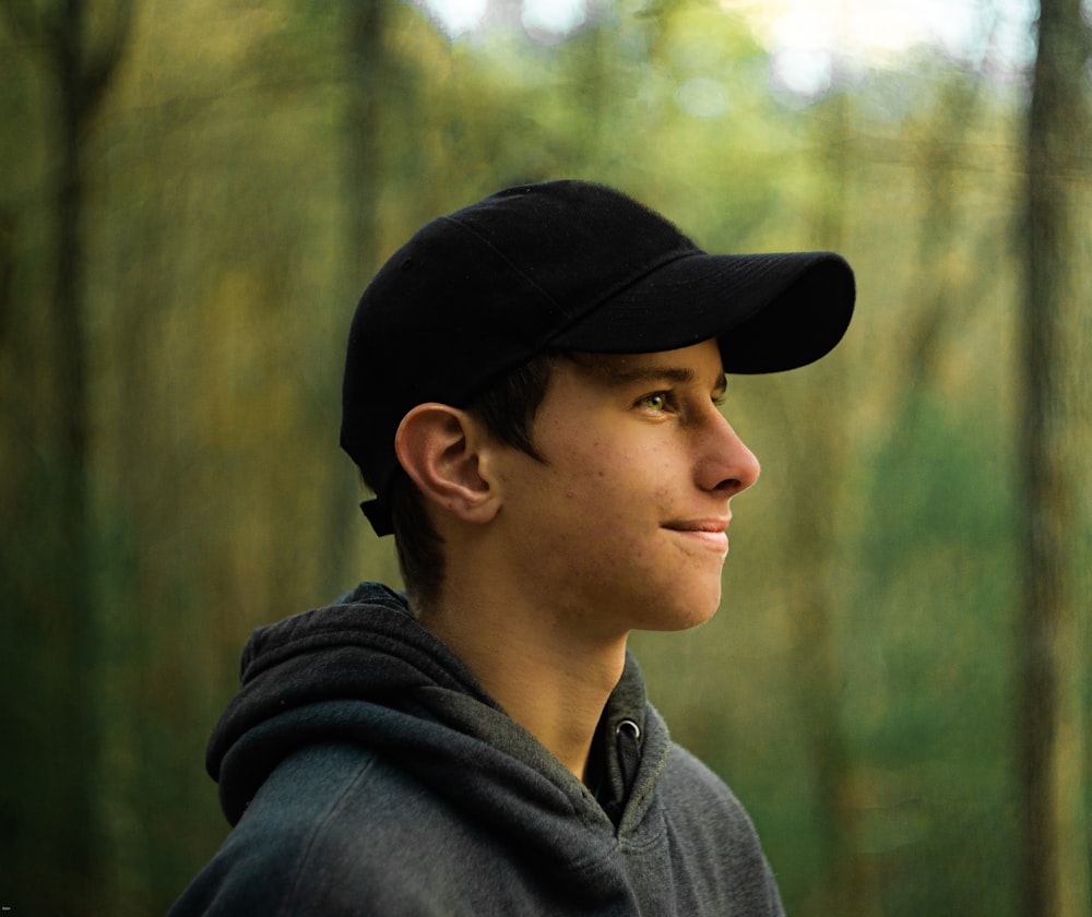 a young man wearing a black hat in the woods