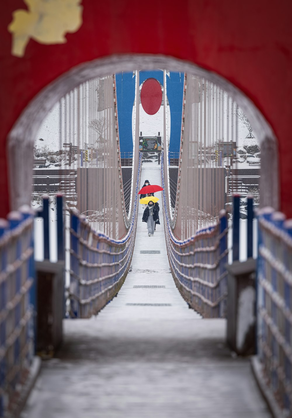 a person with an umbrella walking down a bridge