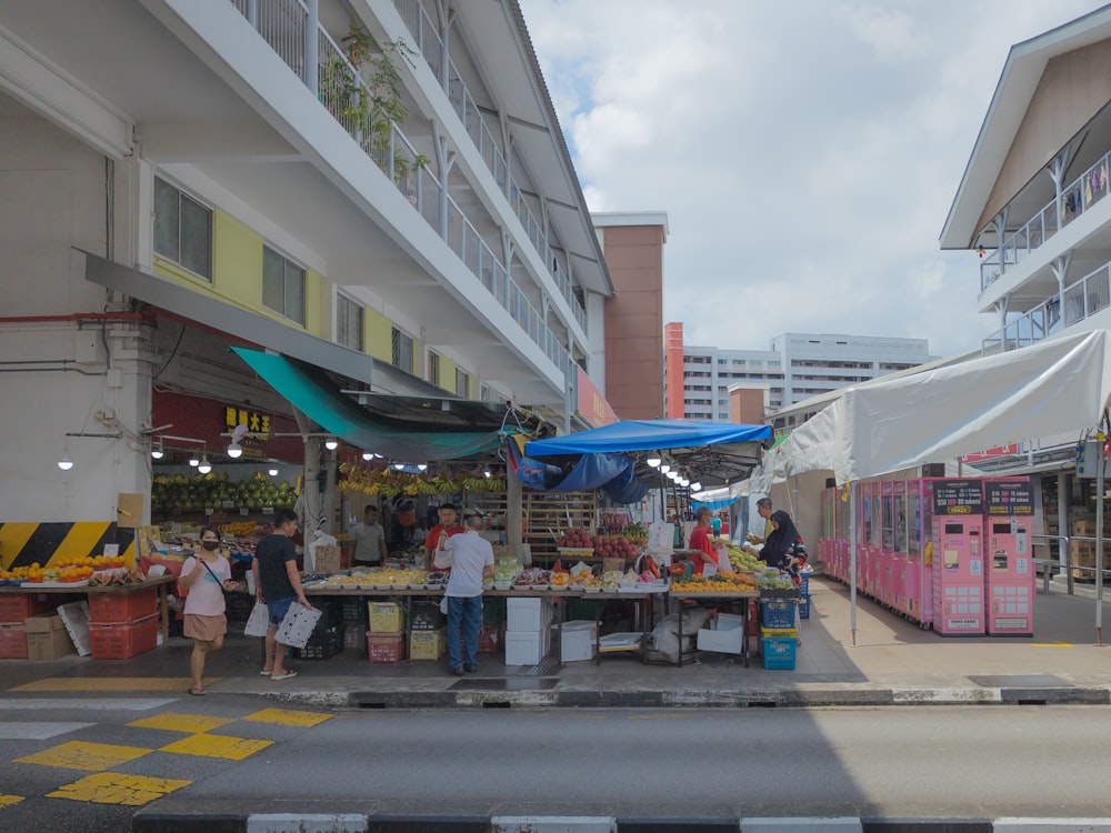 a group of people standing around a fruit stand