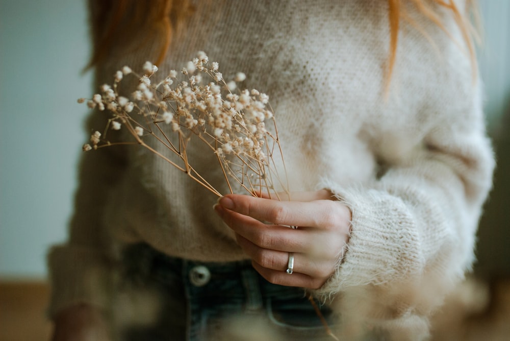 a woman holding a bunch of flowers in her hands