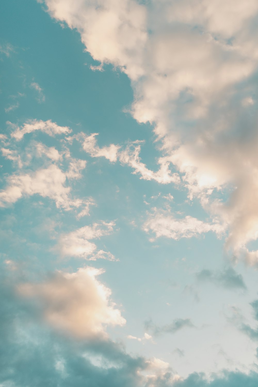 a plane flying through a cloudy blue sky