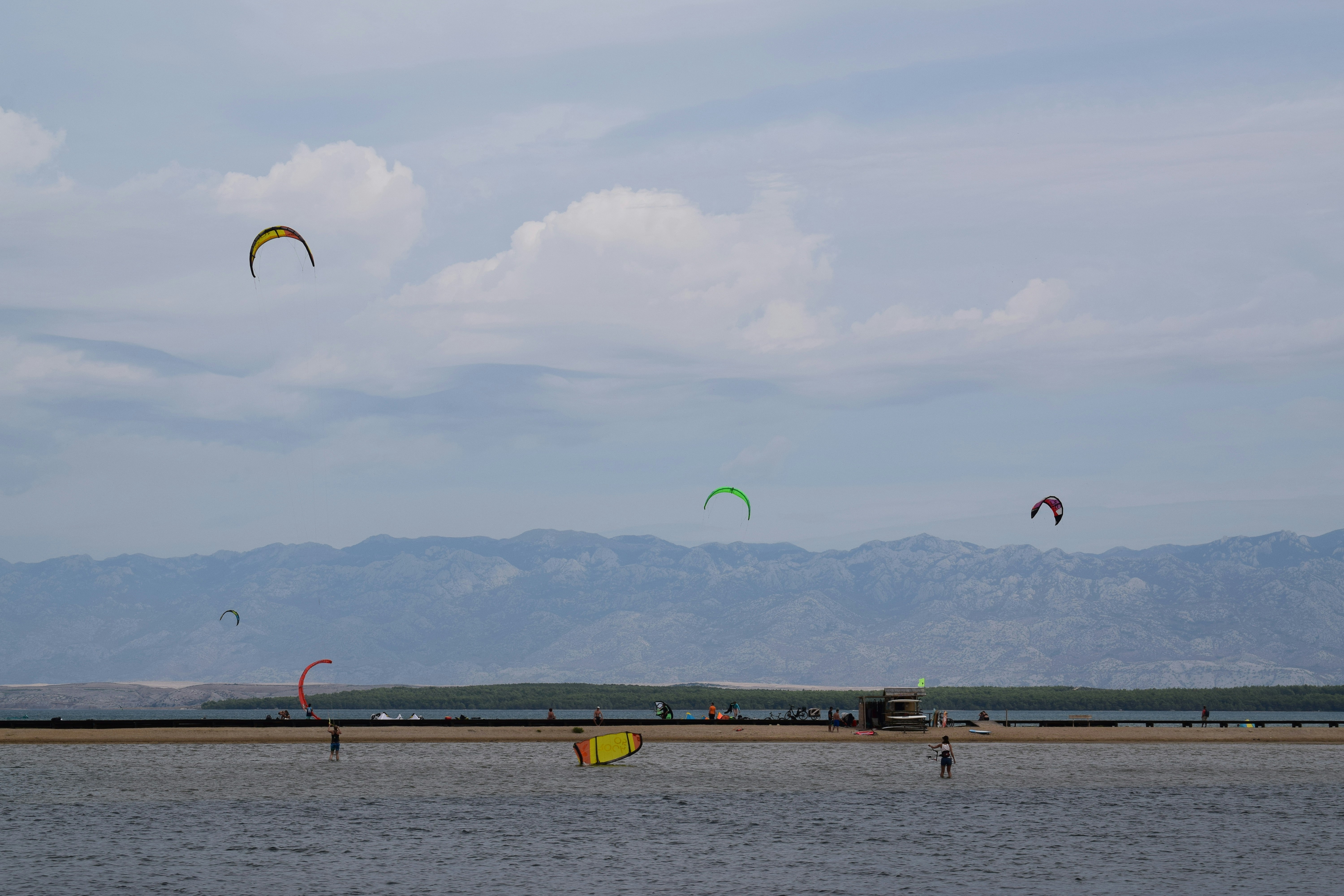 a group of people flying kites over a body of water