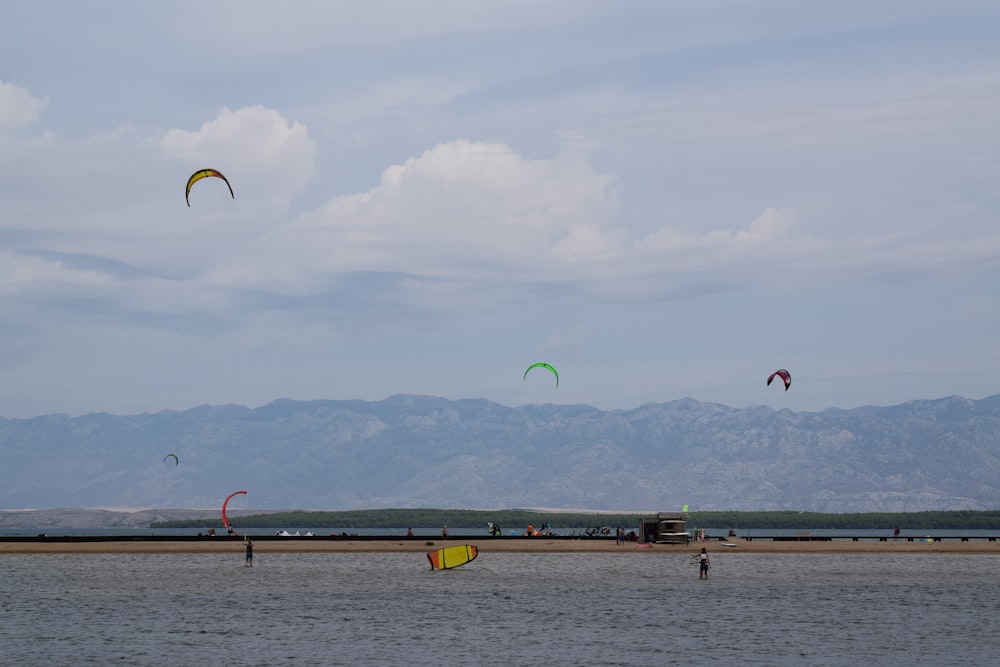 a group of people flying kites over a body of water