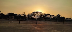 Sunset view over a pickleball court with players finishing a match, capturing the warm colors of the sky.