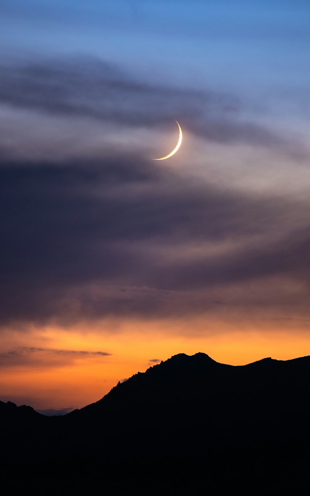 a crescent is seen in the sky over a mountain
