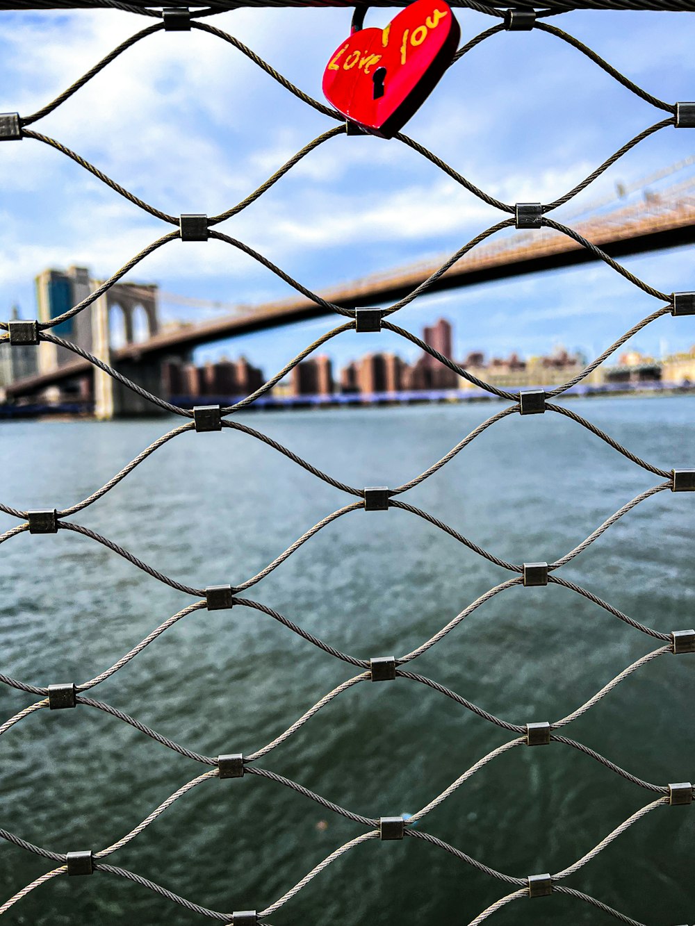 a heart shaped padlock attached to a chain link fence