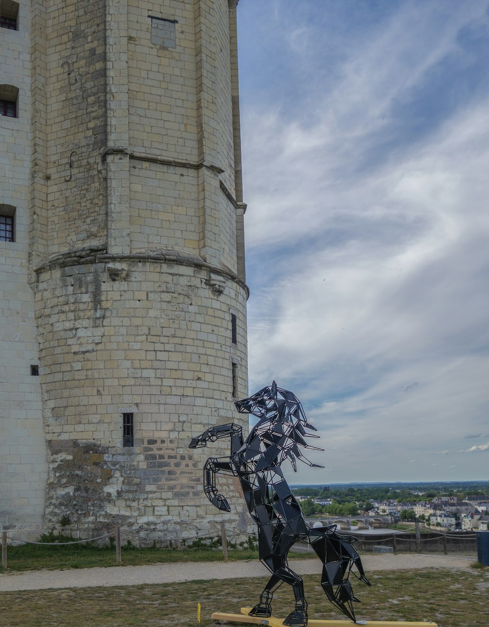 Une statue de cheval est devant une tour