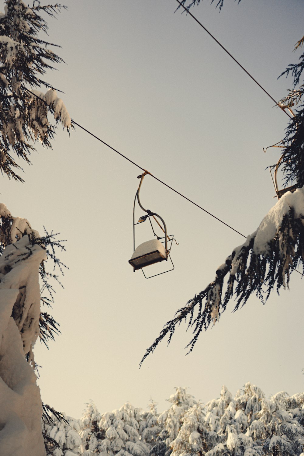 a ski lift hanging from a wire above snow covered trees