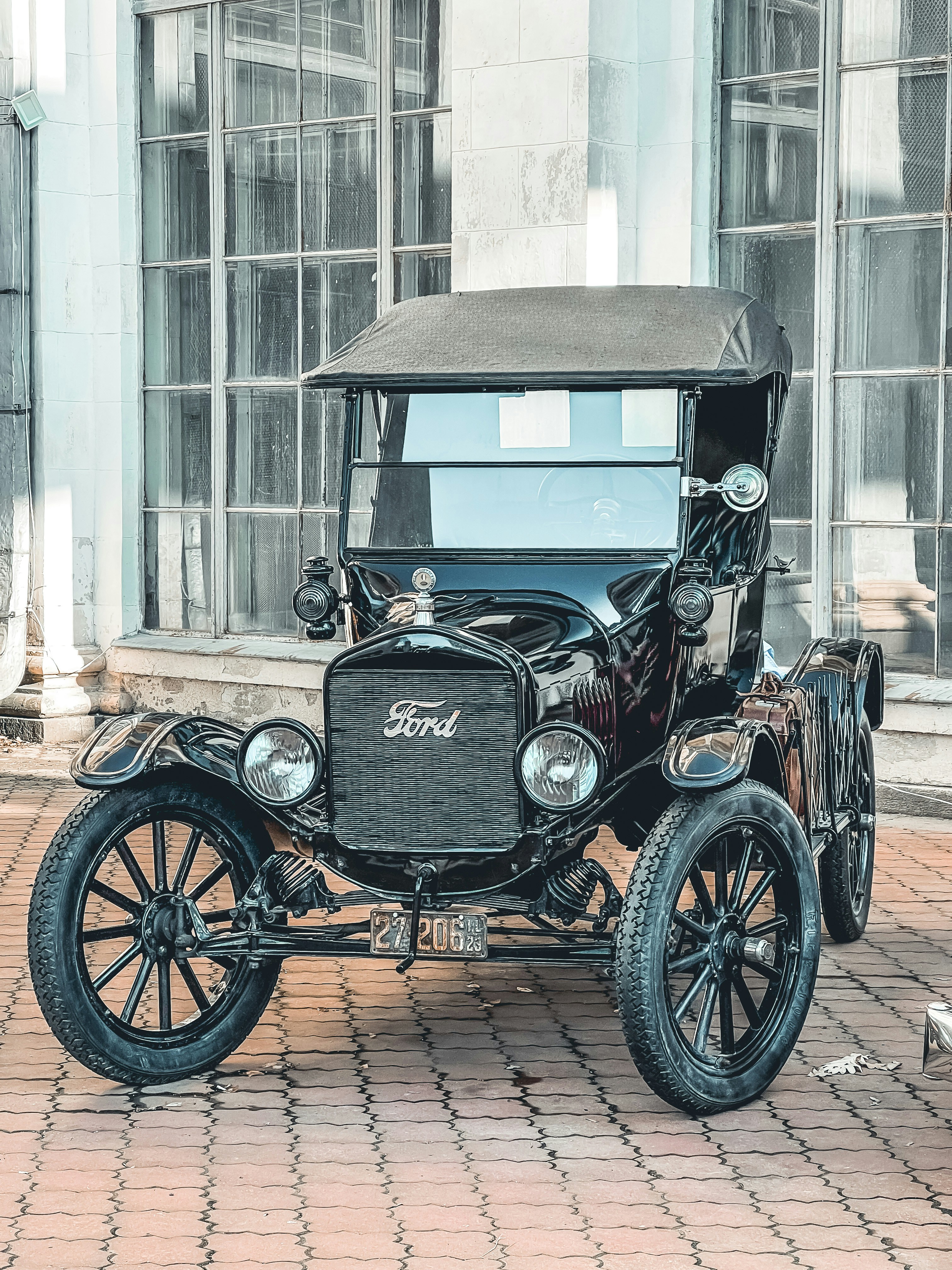 an old fashioned car parked on a brick sidewalk