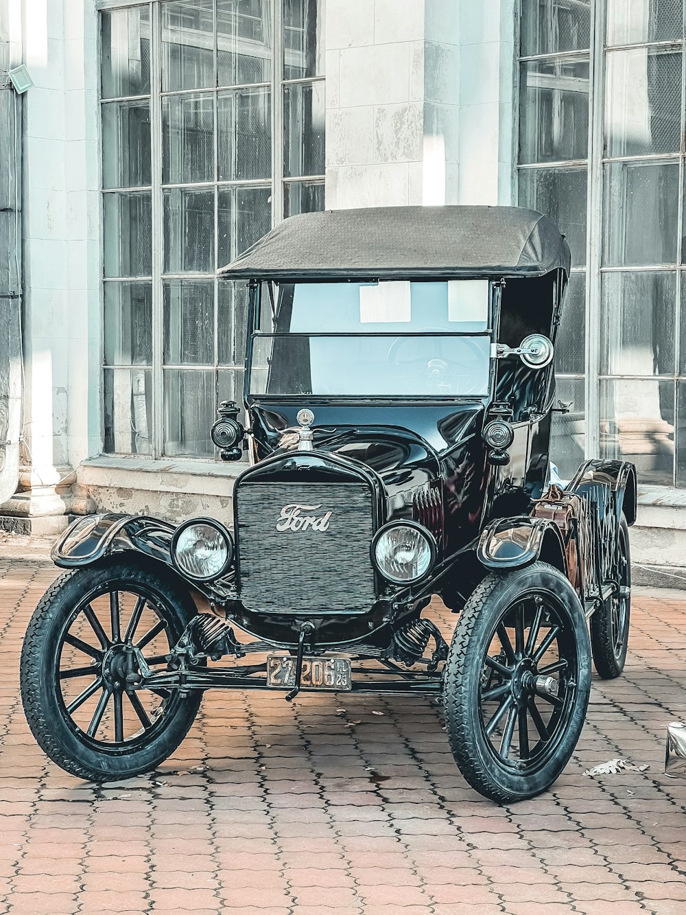 an old fashioned car parked on a brick sidewalk