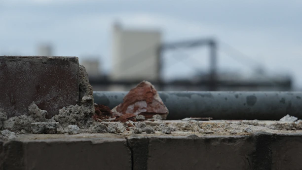 Close-up of industrial cleaning equipment pressure washing a brick wall on a commercial building.