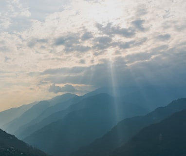 the sun shines through the clouds over the mountains