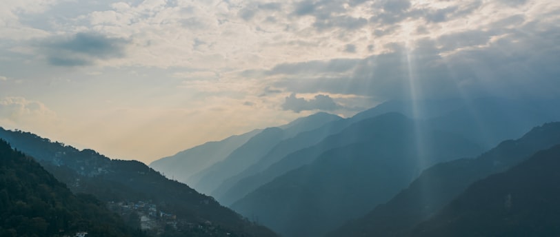 the sun shines through the clouds over the mountains