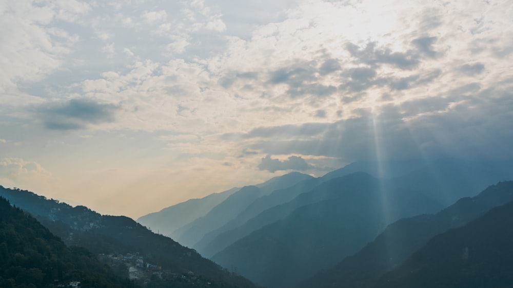 the sun shines through the clouds over the mountains