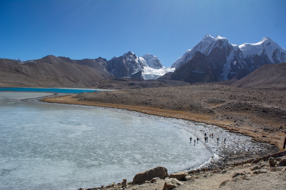 a group of people standing on top of a mountain next to a lake