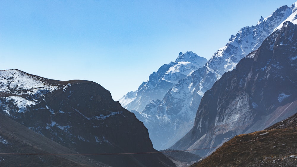 a view of a mountain range with a rope bridge in the foreground