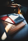 Several publications are stacked together on a chair. Sunlight creates a strong contrast of light and shadow across the items. The top publication is titled 'STANDART'. The setting suggests a cozy, quiet reading nook.
