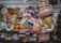 Colorful, striped spinning tops made of wood are hanging from strings in a shop with blurred decorative items in the background.