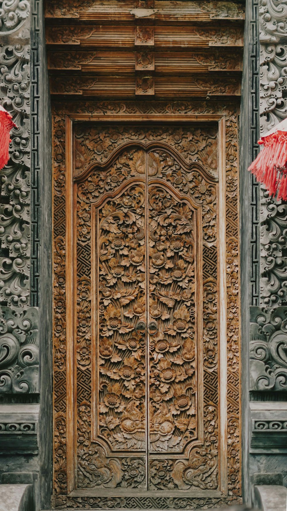 una puerta de madera ornamentada con paraguas rojos colgando de ella