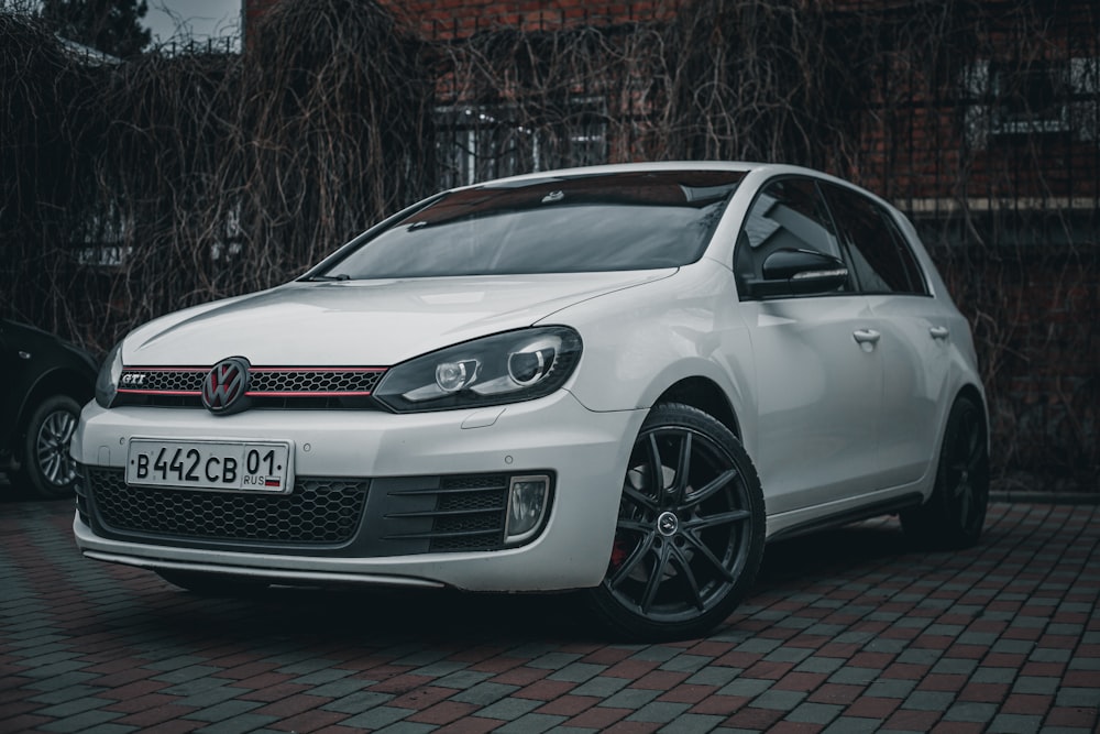 a white car parked in front of a brick building