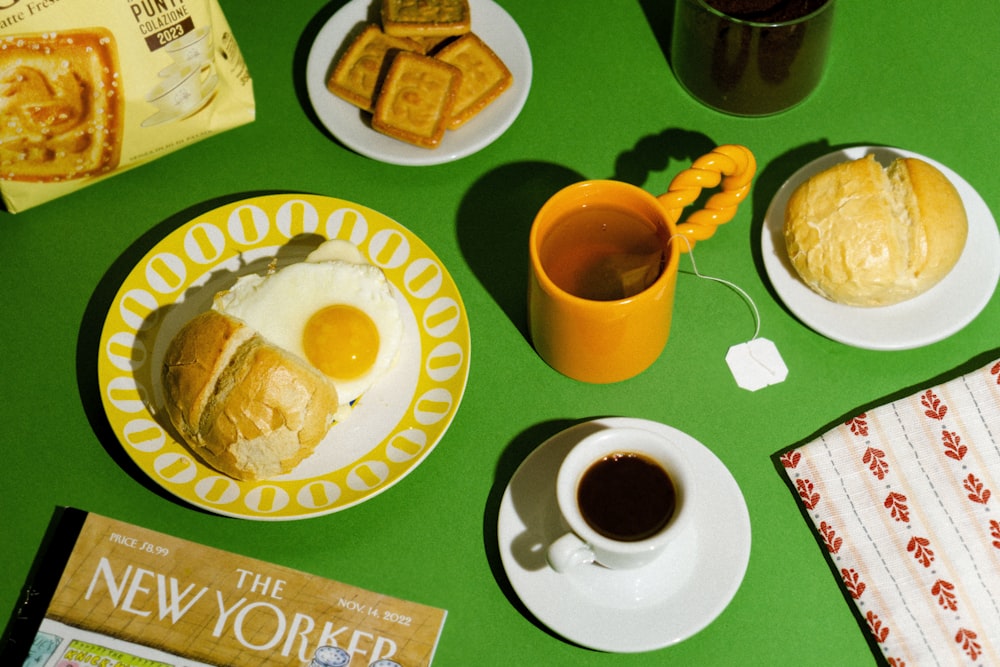 a green table topped with plates of food and a cup of coffee