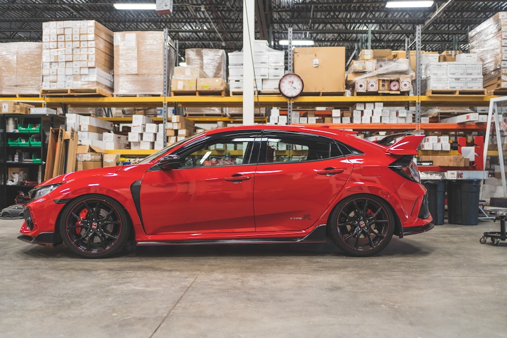 a red car parked inside of a warehouse