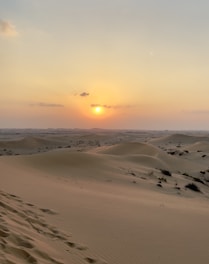 the sun is setting over the sand dunes