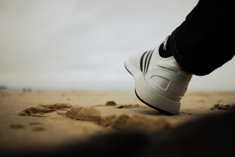 a person standing on a beach with their feet in the sand