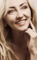 A model wearing a statement ring and matching earrings, smiling in natural light