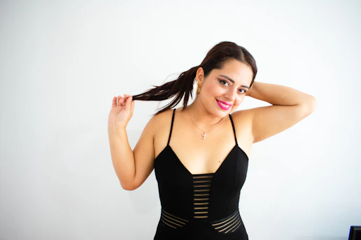 A stylish woman wearing a white and gold Christian-themed t-shirt, smiling softly against a black and burgundy background.