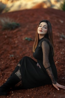 a woman in a black dress sitting on the ground