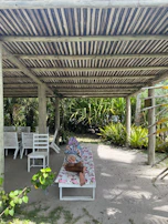 Softly lit photo of a flowing white pareô draped over a sun chair, with tropical greenery in the background.