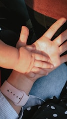 Hands of a mother and child resting on a desk.