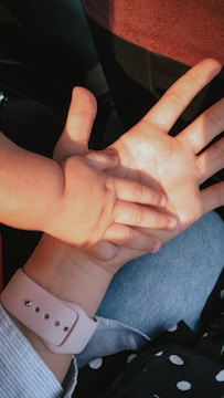 Hands of a mother and child resting on a desk.
