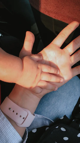 A realistic photo of a gentle feminine hand soothing a child sitting on her lap.
