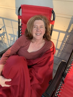 A senior woman smiling warmly while wrapped in a Promise Blanket during a peaceful afternoon.