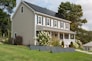 A smiling homeowner standing beside their solar-paneled roof bathed in sunlight.