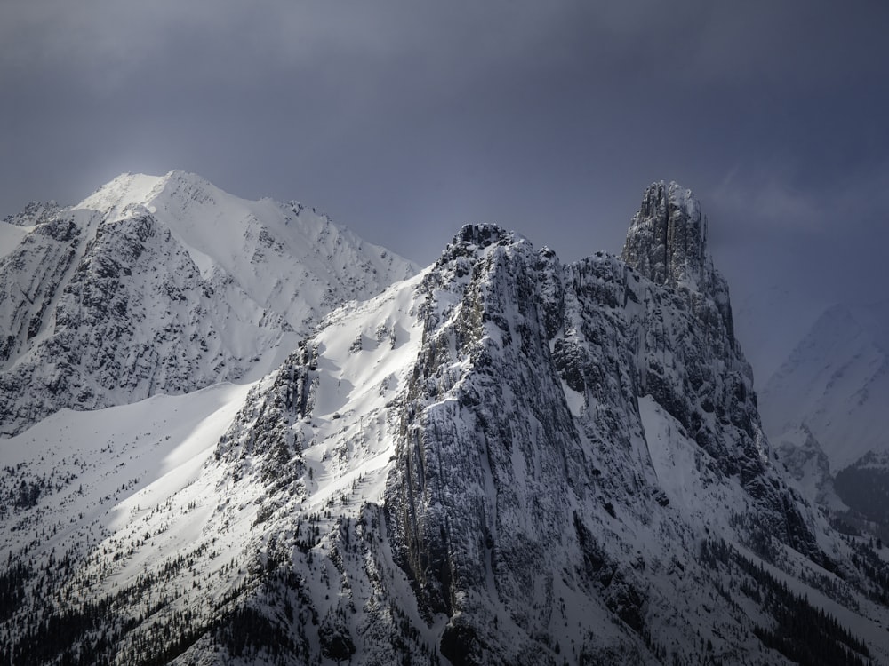 a mountain covered in snow under a cloudy sky