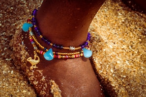 Close-up of a gold anklet with tiny star charms on a sunlit ankle