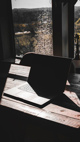 A high-performance laptop open on a wooden table with natural light.
