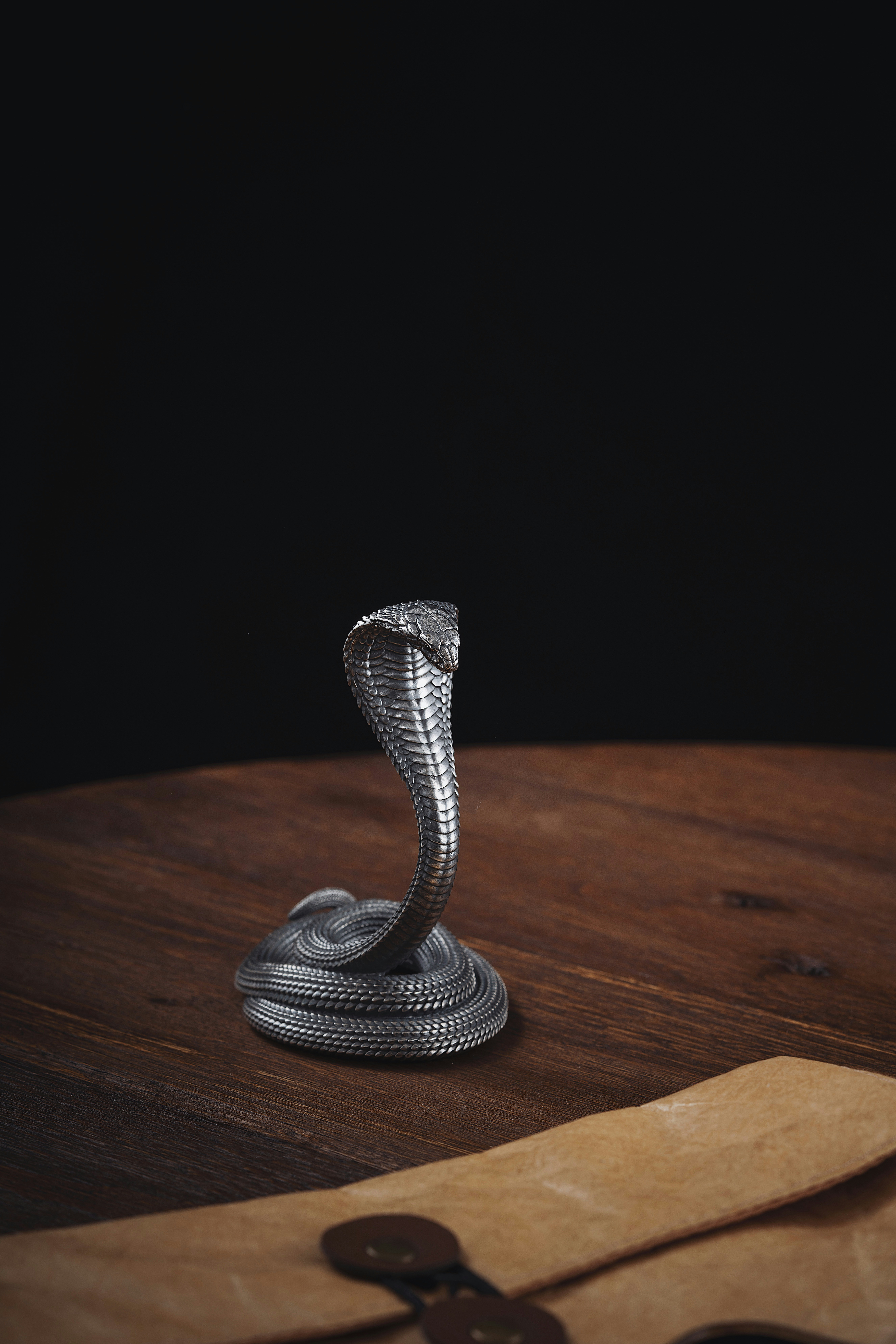 a metal snake on a wooden table next to a pair of scissors