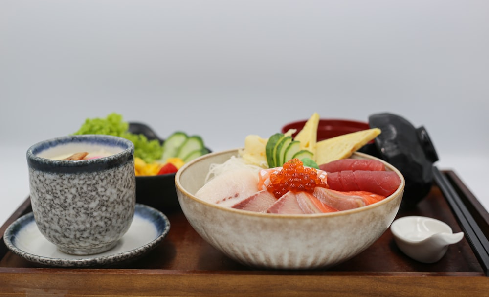 a wooden tray with a bowl of sushi and chopsticks