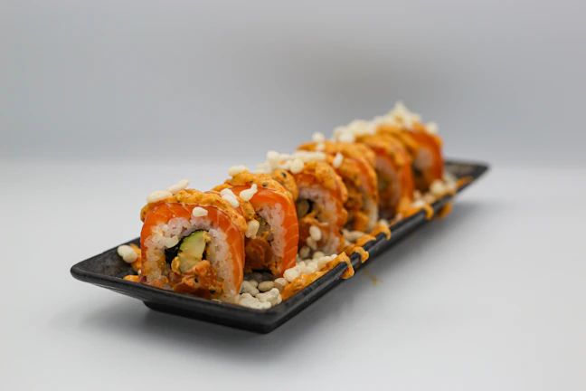 Fresh uramaki rolls topped with bright red tobiko and avocado slices.