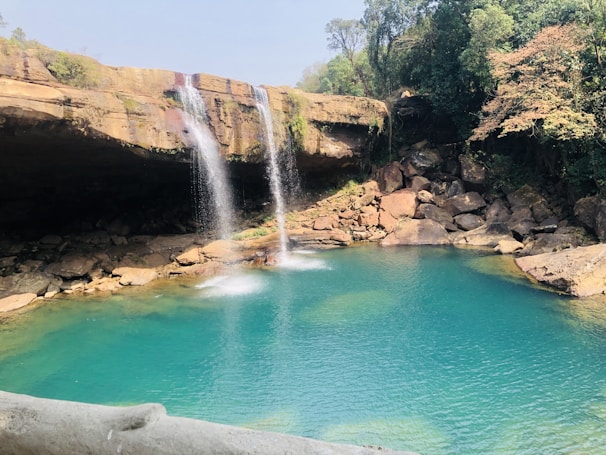 A serene waterfall cascading into a clear pool in the jungle.