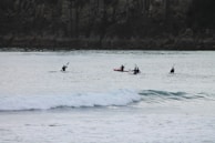 A group of friends kayaking through crystal-clear waters surrounded by rocky cliffs.