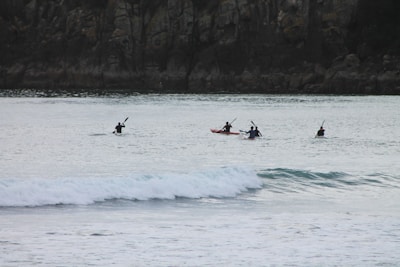 A group of tourists kayaking through calm waters surrounded by cliffs.