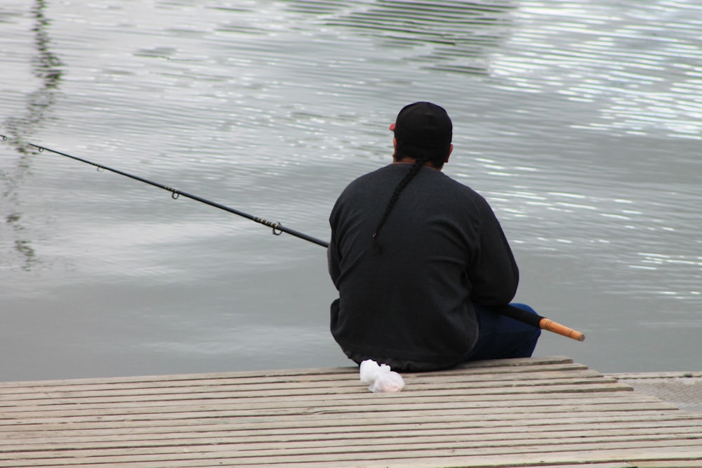 a man sitting on a dock with a fishing rod