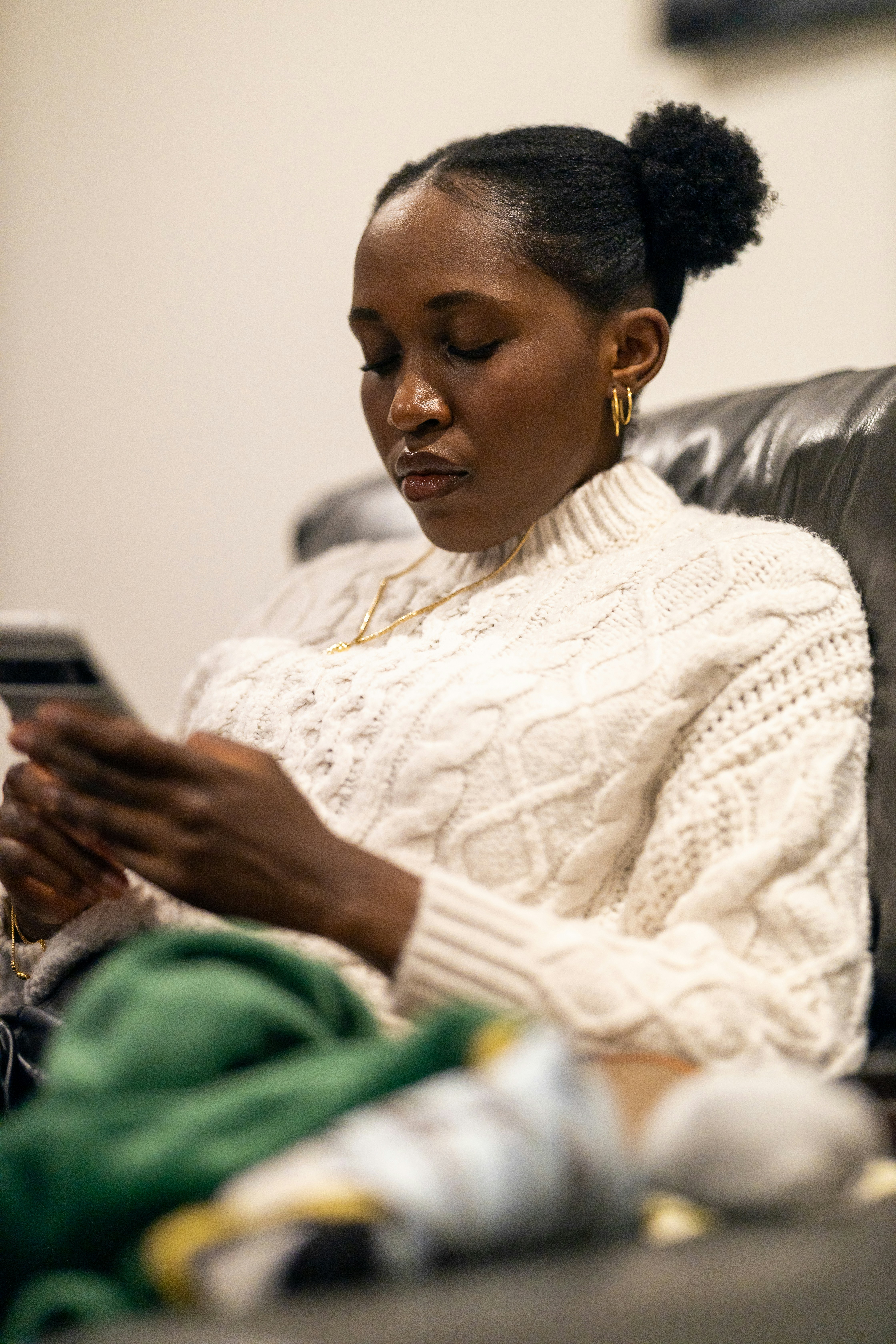 a woman sitting in a chair looking at a cell phone