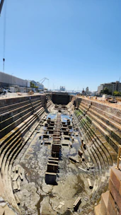 Large drydock facility with a vessel lifted out of water for maintenance.