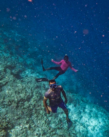 A couple enjoying snorkeling together among colorful coral reefs and fish.